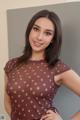 A woman in a brown polka dot dress posing for a picture.