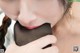 A woman is holding a black object in her mouth.