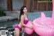 A woman in a pink bikini sitting on an inflatable flamingo.