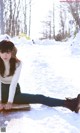 A woman sitting on the ground in the snow.