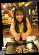 A woman is smiling as she prepares food on a grill.