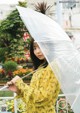 A woman in a yellow kimono holding an umbrella.