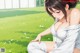 A woman sitting on the grass in a white dress.