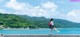 A woman walking along the edge of a concrete wall near the water.