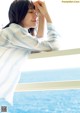 A woman leaning on a railing looking out at the ocean.