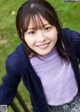 A young woman sitting on a bench in a park.