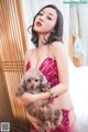 A woman in a pink lingerie holding a small dog.